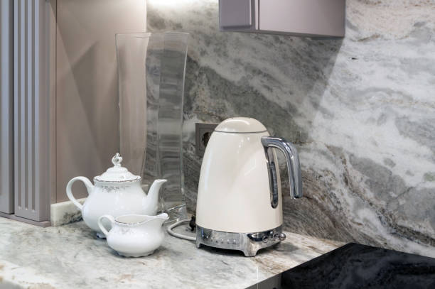 istock beautiful closeup of custom designed kitchen, with marble looking quartz countertop and backsplash. cream electric kettle with porcelain tea accessories on the marble countertop next to the ceramic hob 1290249357