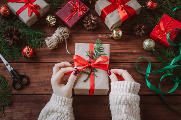 istock Christmas gift wrapping process. Woman decorates box with red ribbon. 1290249372