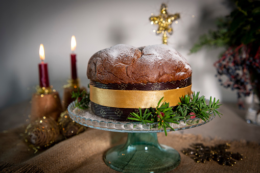A traditional panettone, the famous italian Christmas cake on a table. Blurred Christmas tree and decoration on background