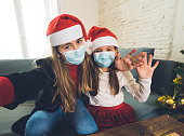 Sad and depressed children with mask at home bored at christmas feeling depressed missing family and friends. COVID-19 Lockdown, quarantine, stay home order, virtual christmas and mental health.