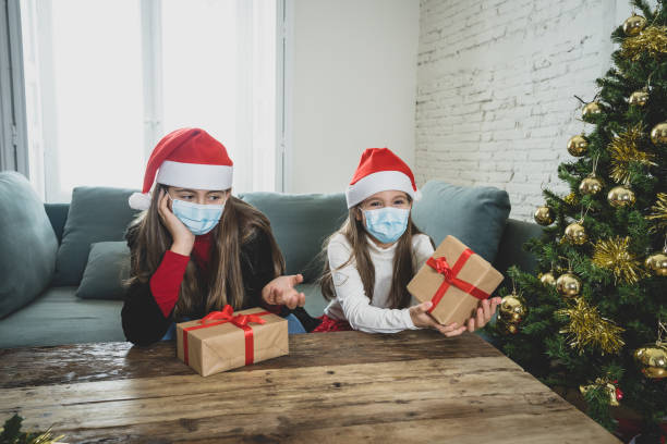 istock Sad and depressed children with mask at home bored at christmas feeling depressed missing family and friends. COVID-19 Lockdown, quarantine, stay home order, virtual christmas and mental health. 1290252777