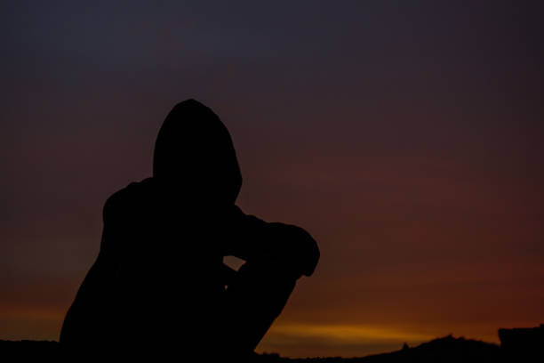istock a boy with a hoody sitting on ground in evening 1290253507