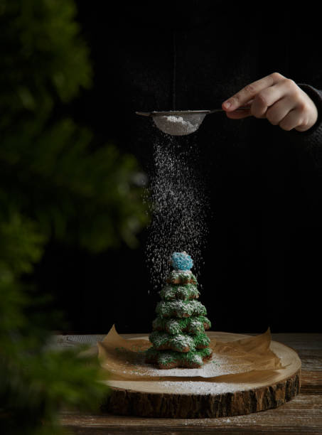 istock hand sprinkles icing sugar on gingerbread tree . Christmas concept 1290256567
