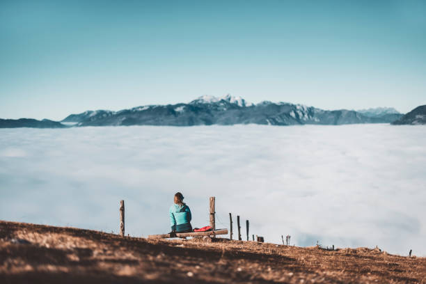 Lonely hiker sitting above the clouds