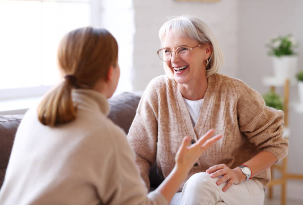 Mother and daughter laughing at joke on sofa
