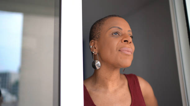 istock Mature woman looking through window at her house 1290258519
