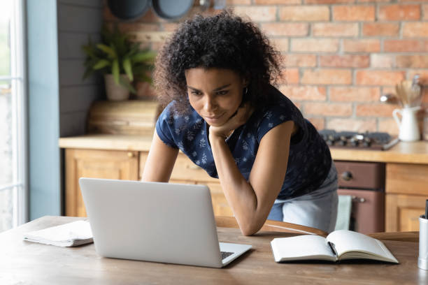 istock Smiling young african american woman working on computer at home. 1290259710
