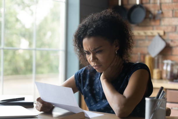 Frustrated young african american woman reading letter with bad news. Frustrated young african american woman reading paper letter with bad news, stressed of getting bank debt or loan rejection notification, feeling confused of termination notice, sitting at table. rejection photos stock pictures, royalty-free photos & images