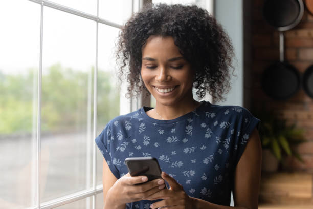 istock Smiling millennial african ethnicity woman using mobile applications. 1290259729