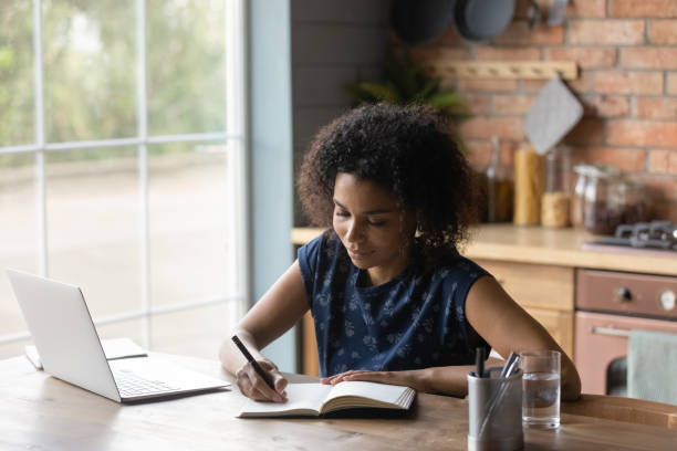 istock Happy millennial biracial lady handwriting in diary. 1290259732
