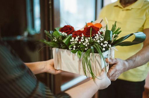 Man delivering flower bouquet for valentines day, woman receiving rose flowers.