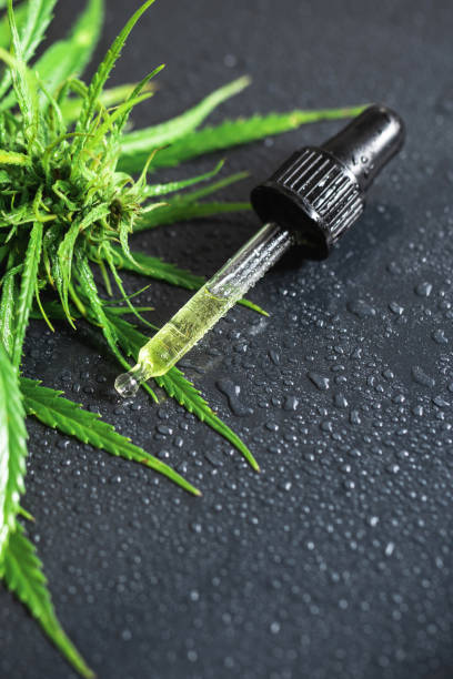 Cannabis plant and pipette with a CBD oil Cannabis plant and pipette with a CBD oil on wet metal surface cbd oil photos stock pictures, royalty-free photos & images