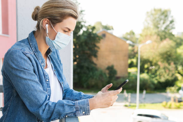istock Woman with a prevention mask on her face is using smartphone 1290264742