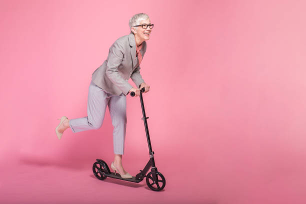 Studio portrait of a senior businesswoman riding a push scooter.