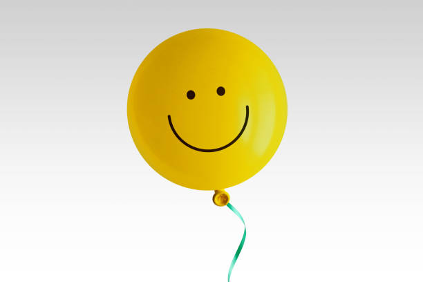 Yellow balloon with smile on white background - Concept of optimism and positive thinking stock photo