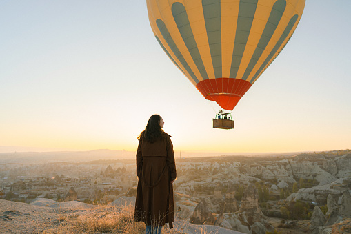 Young Caucasian woman standing and looking at hot air balloons in  Cappadocia in Turkey
