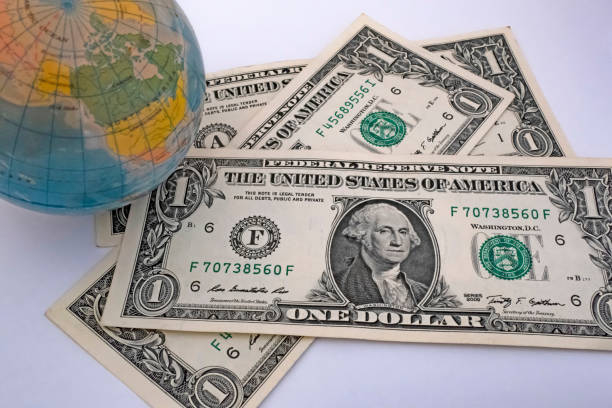 istock Close up US Dollar banknotes with mini earth globe on white background 1290266243