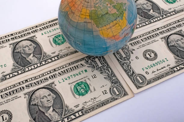 istock Close up US Dollar banknotes with mini earth globe on white background 1290266849