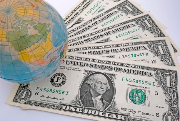 istock Close up US Dollar banknotes with mini earth globe on white background 1290267587