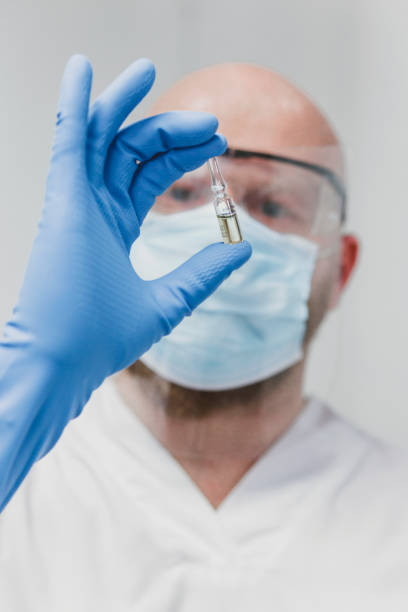 istock Masked scientist holding vial 1290269567