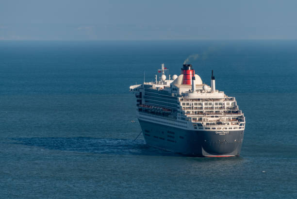 Beautiful Queen Mary 2 cruise ship at Southampton UK port. Aerial panoramic view  towards shipping container terminal and Marchwood Power Plant. Stern of luxury passenger ship with swimming pools. Southampton, UK, 05.04.2024