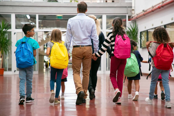 istock Schoolchildren with bright backpacks walking through hallway 1290279328