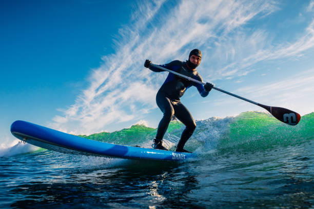 December 8, 2020. Anapa, Russia. Stand Up Paddle surfing on waves. Surfer in wetsuit with paddle ride on sea wave