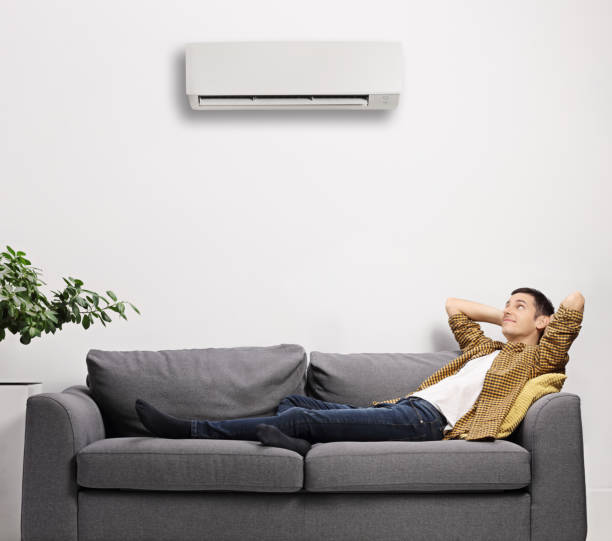 istock Man laying on a sofa with air conditioning unit on the wall 1290280801