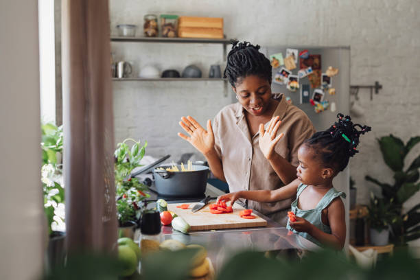 istock Mother and Daughter Cutting a Tomato for Lunch in a Kitchen 1290287574