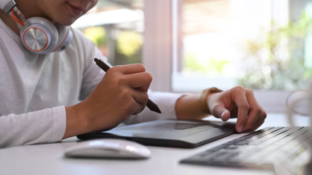 istock Cropped shot of creative designer male using modern wireless tablet with keyboard and stylus pen while working in modern office. 1290288448