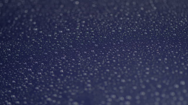 Shiny, lacquered metal sheet covered with water drops