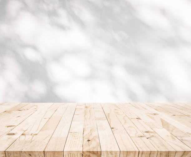 istock White wood table top with shadow of tree leaf on wall background 1290294743