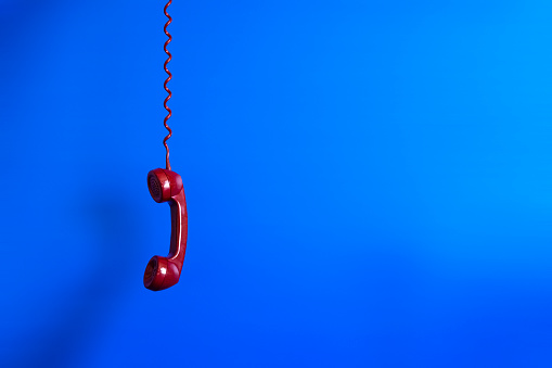 Old red telephone handset swinging. Copy Space