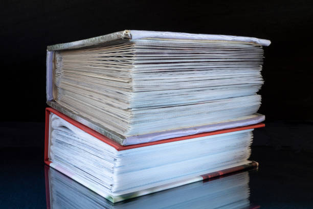 istock Stack of the books rests upon turn blue the table with reflection. 1290304193