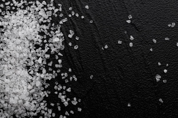istock Coarse sea salt on black background, top view 1290306437