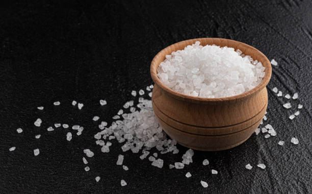 istock Pile of sea salt on black background 1290306440