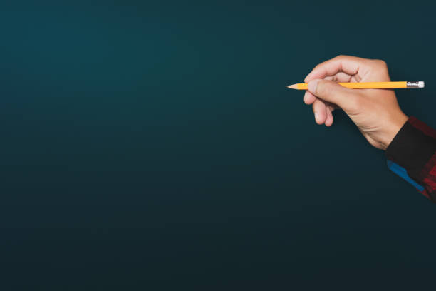 Free Stock Photo of Hand holding a blue-tipped pencil on a dark ...