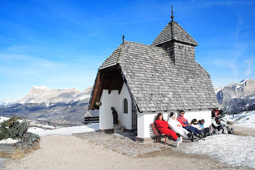 Val Gardena, Italy - January 16, 2007: Skiers rest in front of a small church enjoying the view of the Alps