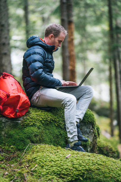 Young man works remotely in lush forest in the morning