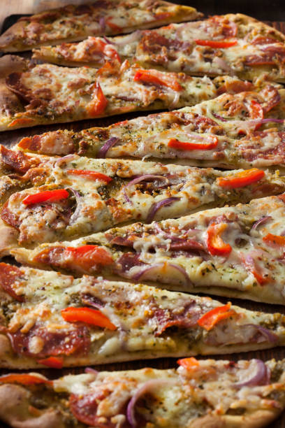 istock Basil Pesto Flat Bread Pizza with Cured Meats, Red Peppers and Spanish Onions 1290311247