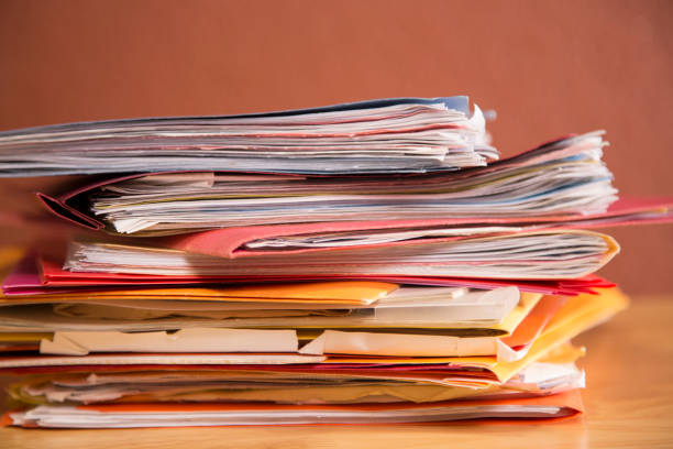 istock Stack of file folders with documents on a wooden top desk. 1290316056