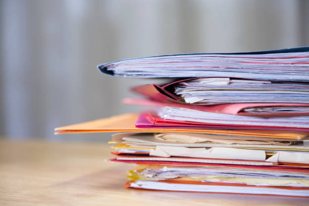 istock Stack of file folders with documents on a wooden top desk. 1290316110