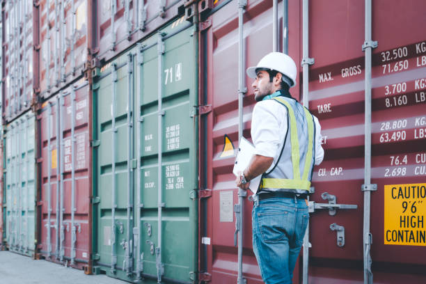 istock Handsome Engineer worker foreman wears personal protective equipment hardhat one hand holding cargo container cover and clipboard check sheet. Working inspection audit logistic transportation concept. 1290320217