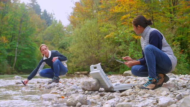 Two female biologist testing the water in a local river