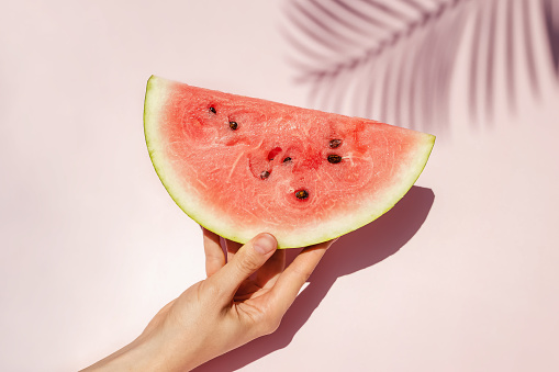 Feminine hand holding slice of ripe watermelon