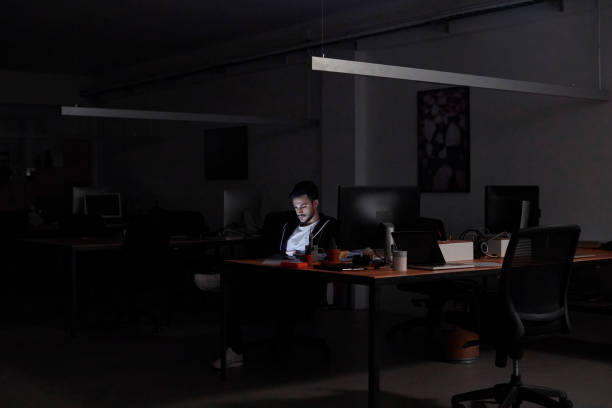istock Businessman By Desk Working Late in Dark Office 1290320622
