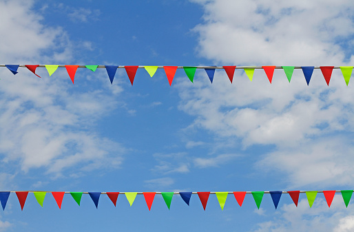 Colorful triangular flags hanging on the blue sky with clouds