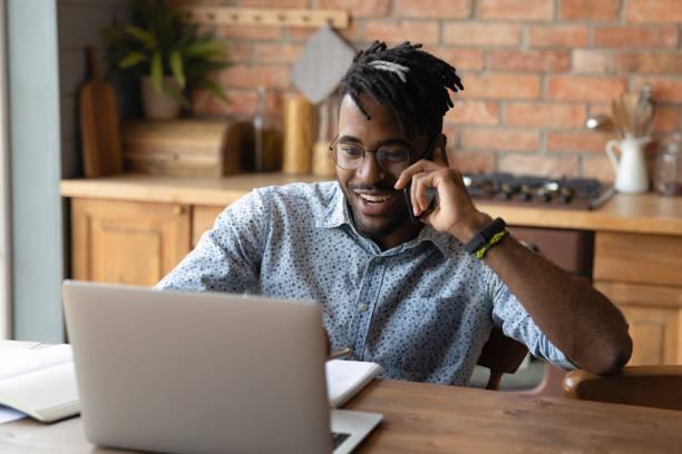 istock Happy young african businessman talking on cellphone working on computer. 1290323427
