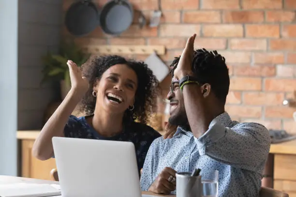 Photo of Emotional euphoric young mixed race couple giving high five.