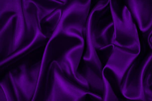 istock Dark purple silk satin fabric. Elegant abstract background in violet colors. Liquid wave or silk wavy folds. 1290327748